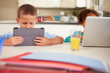 Fototapeta na wymiar Children Using Laptop And Digital Tablet To Do Homework