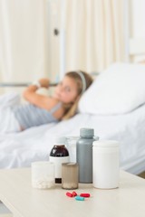 Obraz na płótnie Canvas Medicine bottles on table with girl in hospital