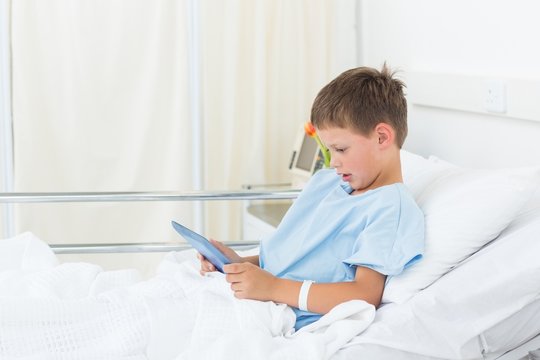 Little boy using digital tablet in hospital
