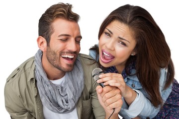 Portrait of a young couple singing into microphone
