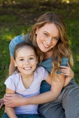 Smiling mother embracing her daughter at park