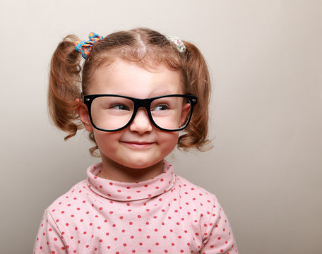 Fun kid girl in glasses looking on empty copy space