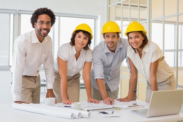 Smiling colleagues working on blueprints at office