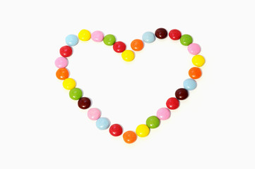 heart of colorful chocolate candies spread on white background