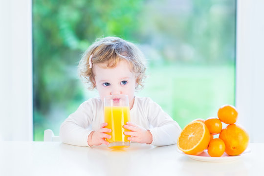 Adorable Toddler Girl Drinking Orange Juice In The Morning