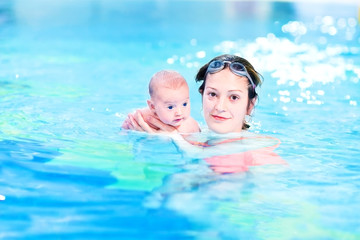 Fototapeta na wymiar Young mother and her newborn baby enjoying swimming together