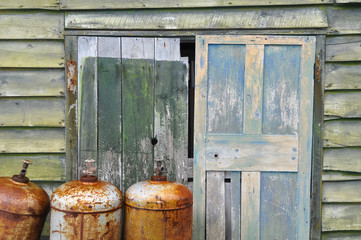 Obraz premium Rusty metal cylinders and weathered shed door