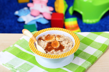 Bowl of porridge for baby and toys  on table, on toys