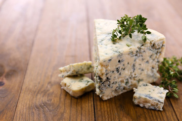 Tasty blue cheese with thyme, on wooden table
