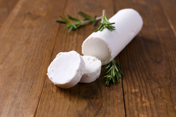 Tasty bushe cheese with rosemary, on wooden table