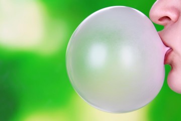 Person doing bubble with chewing gum on bright background