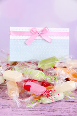 Tasty candies with card on table on bright background