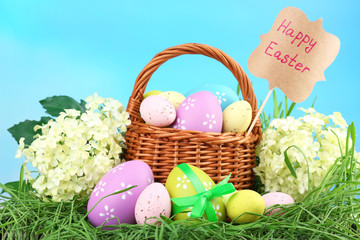 Easter composition with eggs on green grass, on blue background