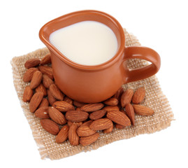 Almond milk in jug with almonds, isolated on white