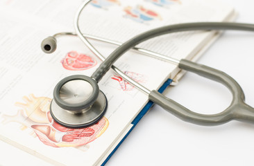 stethoscope and anatomy handbook on white background
