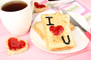 Delicious toast with jam and cup of tea on table close-up