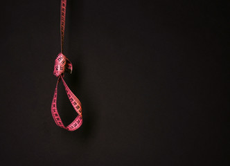 Tape measure noose on dark background - diet concept