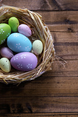 Easter eggs in nest on color wooden background