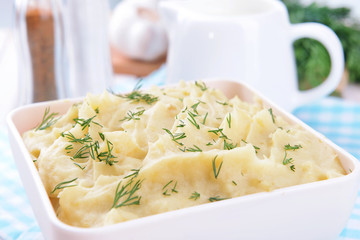 Delicious mashed potatoes with greens in bowl on table close-up