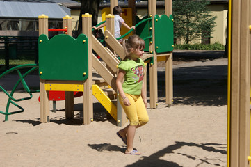 Dziewczynka na placu zabaw biegnąca po piasku. - obrazy, fototapety, plakaty