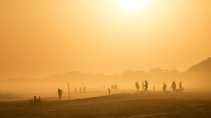 Fototapeta na wymiar Atardecer en playa de uruguay, personas pescando, hora dorada.