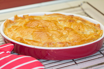 Freshly backed meat pie cooling on metal rack
