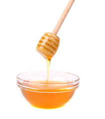 Honey flowing on spoon in a bowl.