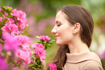 Naklejka premium Portrait of beautiful woman smelling pink flowers on tree