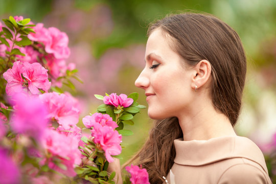 Portrait of beautiful woman smelling pink flowers on tree