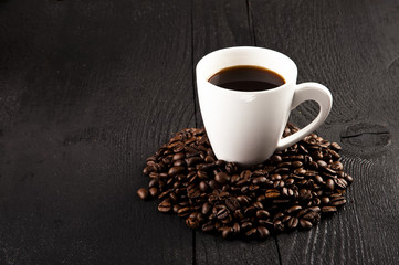 cup of coffee and coffee beans over dark background