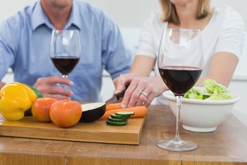 Mid section of couple with wine glasses and vegetables