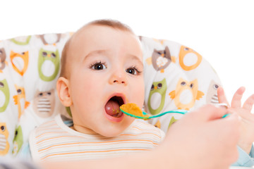 Happy mother feeds hungry baby from a spoon