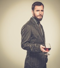 Handsome well-dressed man in jacket with glass of beverage