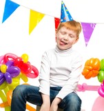 Funny little redhead boy among birthday balloons