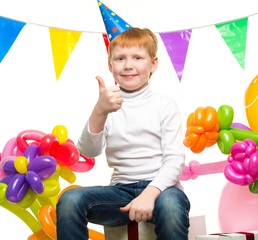 Funny little redhead boy among birthday balloons