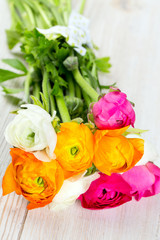 bouquet of white, pink and orange buttercups on wooden table