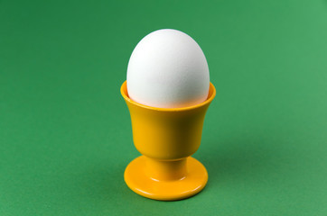 Egg in cup at green background