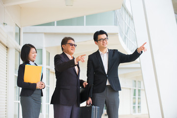 asian business team pointing somewhere in office background