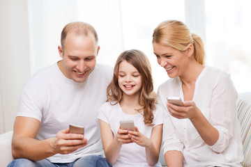 parents and little girl with smartphones at home