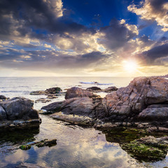 Obraz premium sea wave breaks about boulders at sunset