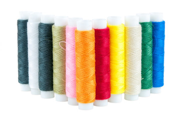 Colored spools of threads on white background
