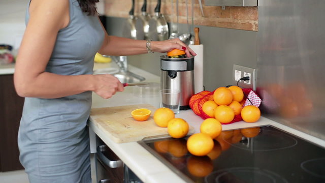 Businesswoman preparing orange juice in kitchen, steadycam shot