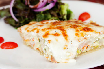 A slice of leek and goats cheese quiche on a plate with crispy l