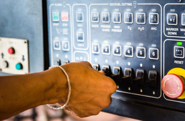 A worker operating a gas cutting machine with a control panel