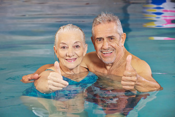 Paar Senioren hält Daumen hoch im Schwimmbad