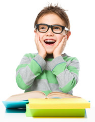 Astonished little boy is reading a book