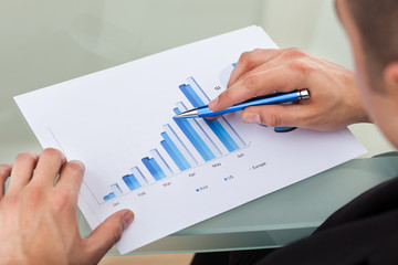 Cropped image of businessman analyzing bar chart with pen