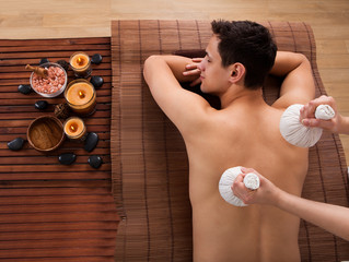 Young Man Receiving Massage With Stamps In Spa