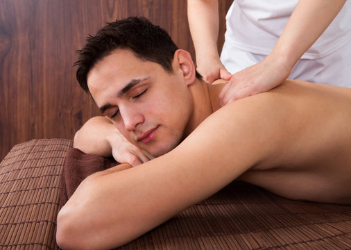 Relaxed Man Receiving Shoulder Massage In Spa