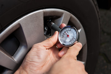 Mechanic Checking Tire Pressure Using Gauge